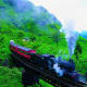 Steam locomotive train crossing bridge through lush green mountains in Nuwara Eliya, Sri Lanka